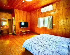 a bedroom with a bed and a television in it at Fong Chou Chalet in Sanyi