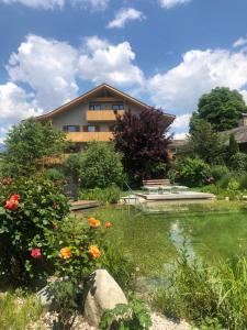 a building with a pond and flowers in front of it at Linderhof in Natz-Schabs