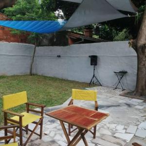 einen Tisch und zwei gelbe Stühle sowie einen Tisch, einen Tisch und einen Tisch. in der Unterkunft casa con piscina, alojamiento hasta 12 personas in Asunción