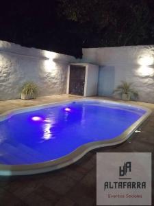 una gran piscina azul en un patio por la noche en casa con piscina, alojamiento hasta 12 personas, en Asunción