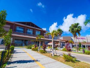 a building with palm trees in front of a street at Allstay CHIBANA in Okinawa City