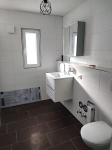 ein Badezimmer mit einem weißen Waschbecken und einem WC in der Unterkunft Ferienwohnung Lange in Brilon