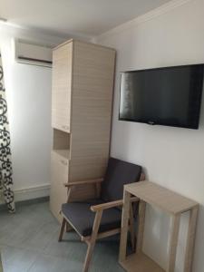 a room with a chair and a desk and a tv at Casa Marronne in Costinesti