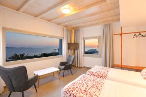 a hotel room with a bed and a large window at O Lofos Luxury Boutique Suites in Agios Stefanos
