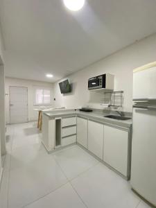 a kitchen with white appliances and a white tile floor at Fama Suite YB in La Rinconada