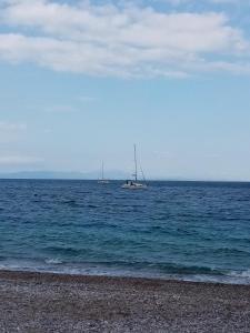 two boats floating in the water near a beach at KOTSIFAS ROOMS in Tyros