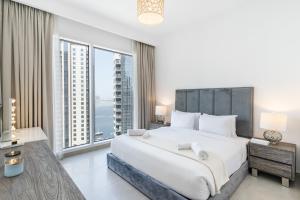 a bedroom with a large bed and large windows at Creek Horizon - 2BR Apartment - Allsopp&Allsopp in Dubai