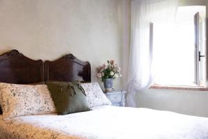 Il Casale del Duca في أوربينو: غرفة نوم مع سرير ونافذة مع ترتيب الزهور