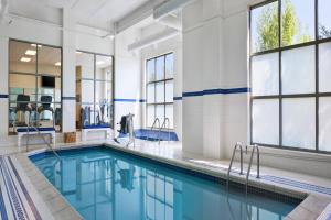 a pool with blue water in a building with windows at Sheraton St Paul Woodbury Hotel in Woodbury