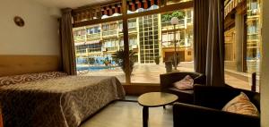 マルベーリャにあるPrimera línea de playaのベッドと椅子、大きな窓が備わるホテルルームです。