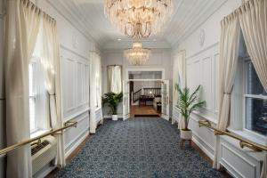 a hallway with a chandelier and a room with windows at The Madison Hotel in Morristown