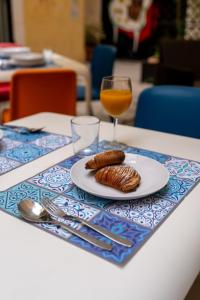 a table with a plate of food and a glass of orange juice at Cortile dei Giusti - Combo Guesthouse in Palermo