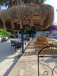 een patio met een tafel en stoelen onder een rieten parasol bij Işıl Suit Apart Otel in Dalyan