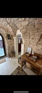 a room with a stone wall with a wooden table at DOMMO ASULETTA in Bosa
