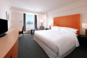a hotel room with a large bed and a television at Sheraton Miyako Hotel Osaka in Osaka