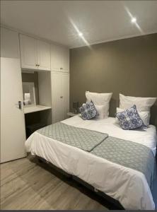 1 dormitorio con 1 cama grande con almohadas azules en Grace Gardens - Grace en Pretoria
