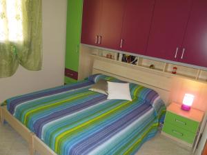 サン・ヴィート・ロ・カーポにあるCasa Vacanze Coralのベッドルーム(ベッド1台、紫と緑のキャビネット付)