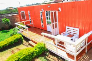 a deck with a bed and a house at The Red Container-Off Grid in Ngong