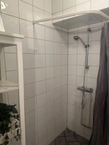 uma casa de banho com um chuveiro de azulejos brancos e uma cabeça de chuveiro. em 35m2 apartment in central oslo em Oslo