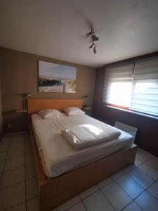 een groot bed in een slaapkamer met een raam bij Aux 3 P'tits Wallons in Middelkerke