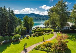 um jardim com um lago ao fundo em Strandhotel Habich em Krumpendorf am Wörthersee