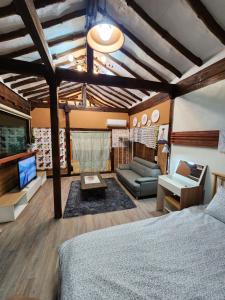 Kims House Andong في آندونغ: غرفة نوم بسرير واريكة وتلفزيون