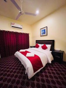 a bedroom with a large bed with red pillows at DANA HOTEL in Sharjah