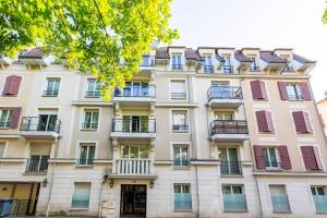 - un grand bâtiment blanc avec des fenêtres et des balcons dans l'établissement Cosy appart entre Paris et Disneyland, à Villiers-sur-Marne