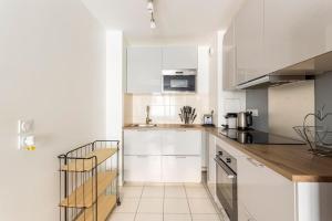 a kitchen with white cabinets and a wooden counter top at Cosy appart entre Paris et Disneyland in Villiers-sur-Marne