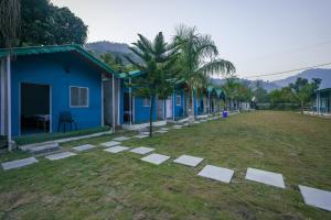 a row of blue houses with trees and grass at H7Stay Luxury Cottages And Camps, Rishikesh in Rishīkesh