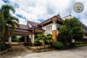 a large white house with a tree in front of it at Ariya inn Chiangrai in Chiang Rai