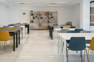 une salle à manger avec des tables, des chaises et des étagères dans l'établissement micampus Avenida del Puerto - Residencia de Estudiantes, à Valence