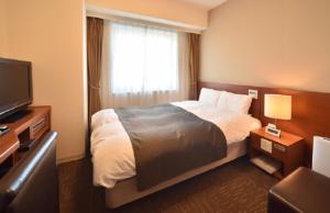 Dormy Inn Tomakomai في توماكوماي: غرفه فندقيه سرير وتلفزيون
