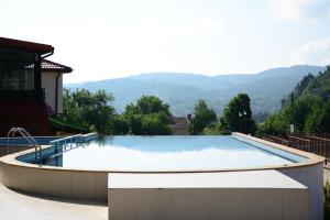 a large swimming pool with mountains in the background at Апартамент Езерото in Tryavna
