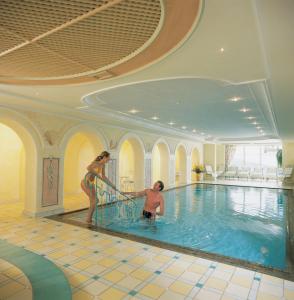 a man and a woman standing in a swimming pool at Hotel Garni Serfauserhof in Serfaus