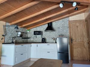 a kitchen with white cabinets and a black refrigerator at CON ENCANTO in Cabezuela del Valle