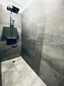 a bathroom with a shower with a gray wall at La King Le 50 Suites and SPA in Bordeaux