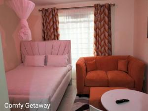 a living room with a couch and a chair at Comfy Getaway STUDIO apartment near JKIA & SGR with KING BED, WIFI, NETFLIX and SECURE PARKING in Syokimau