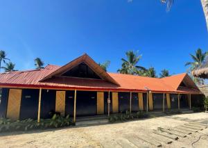盧納將軍城的住宿－Dawn Patrol Siargao，一座红色屋顶和棕榈树的建筑
