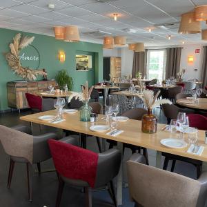 un ristorante con tavoli in legno e sedie rosse di Appart'Hotel Prestige Odalys Nakâra a Cap d'Agde