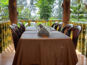 PurbbadulkiにあるSundarban Tiger Roar Resortの木製テーブル(椅子付)と茶色のテーブルクロス