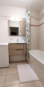 a bathroom with a sink and a tub and a mirror at Superbe appartement en résidence avec piscine. in Albertville