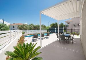 eine Terrasse mit einem Tisch, Stühlen und einem Pool in der Unterkunft Pinia Apartments in Vodice