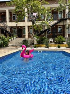 une petite fille dans un radeau rose dans une piscine dans l'établissement Гостевой дом Асель, à Cholpon-Ata