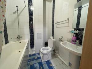 a bathroom with a white toilet and a sink at Three bedroom apartment with 2 showers in Tashkent