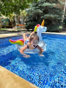 un niño pequeño montado en un tobogán de agua en una piscina en Гостевой дом Асель en Cholpon-Ata