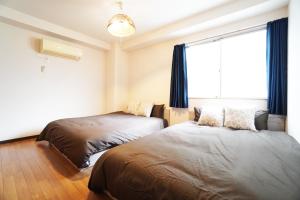 - une chambre avec 2 lits et une fenêtre dans l'établissement Akimi building, à Osaka