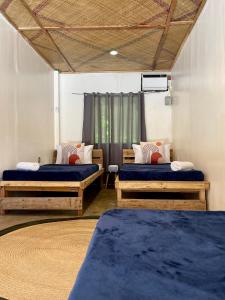 a room with three beds and a curtain at Dawn Patrol Siargao in General Luna