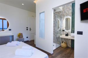 sypialnia z białym łóżkiem i łazienką w obiekcie Albergo Auralba w mieście San Vito lo Capo