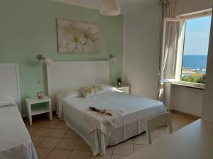 a bedroom with a white bed and a window at Hotel Holiday Bambù in Marciana